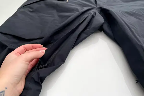 A person lifts the flap on the zippered pocket on the Backcountry CrestCarver Men