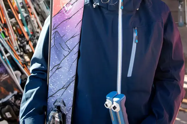 Person wearing ski jacket holding skis