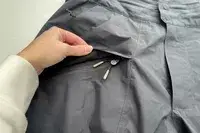 A person lifts the flap on the zippered pocket on the Backcountry CrestCarver Men