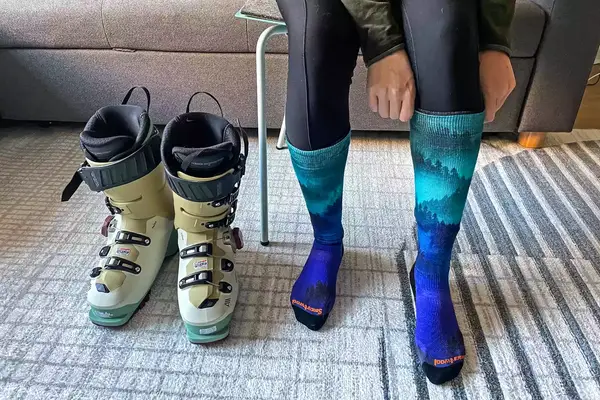 A person sitting in a chair putting on the Smartwool Women