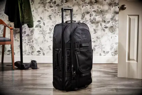 A person wheels the Away The Outdoor Rolling Duffel 85L between cones