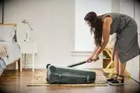 A person hits the Away The Outdoor Rolling Duffel 85L with a baseball bat