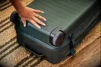 A person touches the bottom of the Away The Outdoor Rolling Duffel 85L