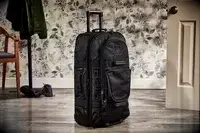 A person adjusts the strap on the Away The Outdoor Rolling Duffel 85L