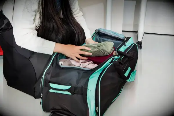 A person unzips the pocket on the Away The Outdoor Rolling Duffel 85L