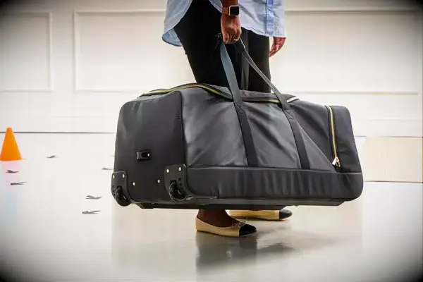 Person throwing Travelers Club Xpedition Multi-pocket Upright Rolling Duffel Bag off a counter