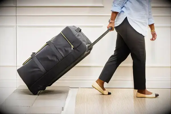 Person throwing Travelers Club Xpedition Multi-pocket Upright Rolling Duffel Bag off a counter