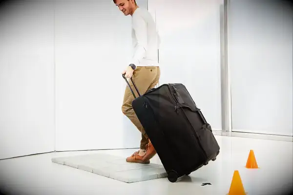 Person wheeling Tumi Alpha 3 Large Split 2-Wheeled Duffel onto pavers