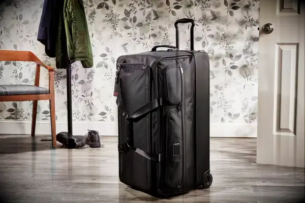 Tumi Large Split 2 Wheeled Duffel in front of floral wallpaper and coat rack