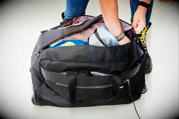 Tumi Large Split 2 Wheeled Duffel in front of floral wallpaper and coat rack