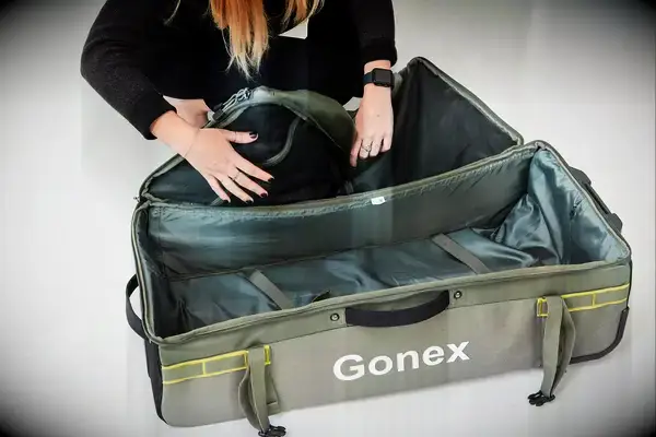 Person zipping compartments of the Gonex Rolling Duffel Bag With Wheels