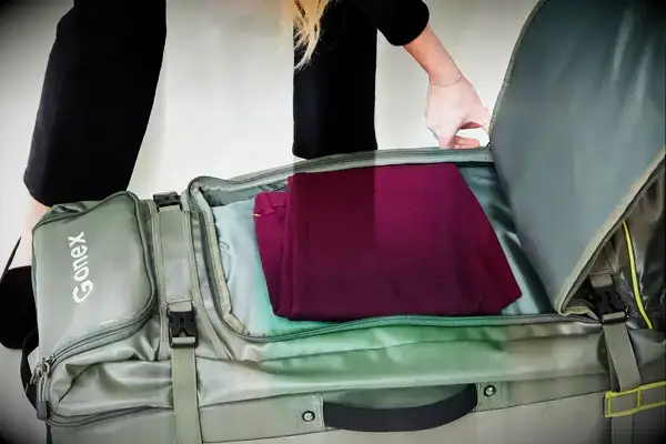 Person zipping packed Gonex Rolling Duffel Bag With Wheels