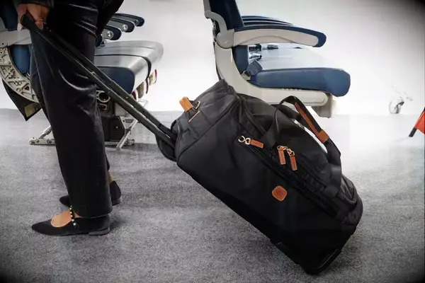 Gonex Rolling Duffel Bag With Wheels displayed upright in front of floral wallpaper