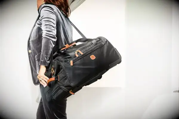 Person zipping compartments of the Gonex Rolling Duffel Bag With Wheels