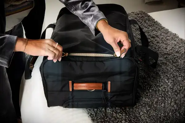 Person zipping packed Gonex Rolling Duffel Bag With Wheels