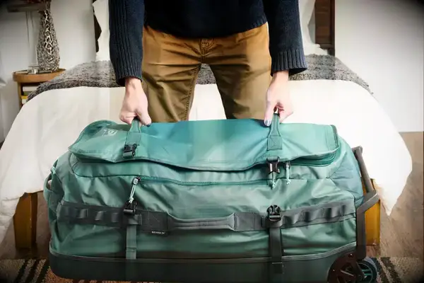 Hands opening Samsonite Just Right Weekend Wheeled Duffel zippered compartment