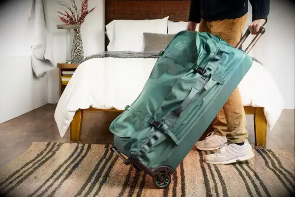 A person tilting the REI Co-op Big Haul 34-inch Rolling Duffel