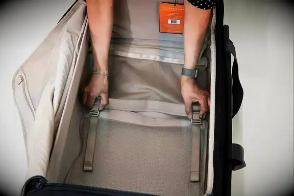 A hand holding the strap of the REI Co-op Big Haul 34-inch Rolling Duffel