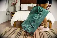A person tilting the REI Co-op Big Haul 34-inch Rolling Duffel