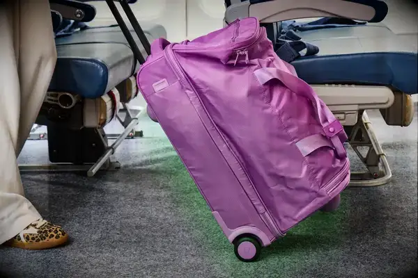 A person wheeling the Vera Bradley Adair Rolling Duffel Bag through an aisle