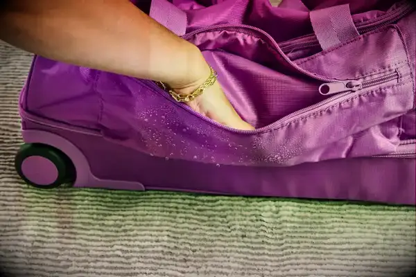 A person putting their hand into a pocket of the Vera Bradley Adair Rolling Duffel Bag