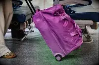 A person wheeling the Vera Bradley Adair Rolling Duffel Bag through an aisle