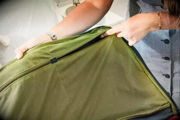 A person unzips the pocket on the Away The Outdoor Rolling Duffel 85L