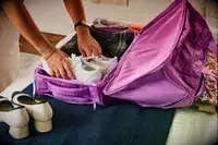 A person packing shoes into the Vera Bradley Adair Rolling Duffel Bag