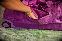 A person putting their hand into a pocket of the Vera Bradley Adair Rolling Duffel Bag