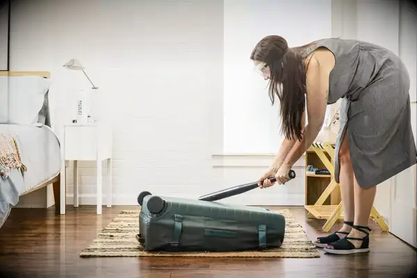 A person hits the Away The Outdoor Rolling Duffel 85L with a baseball bat