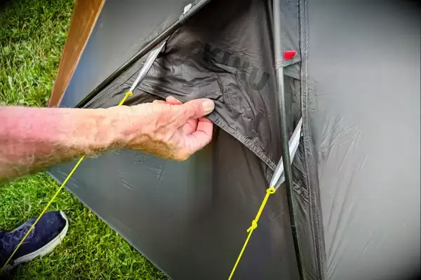 A person pulls a section of the Kuiu Mountain Star 2 Person Tent with the brand logo on it