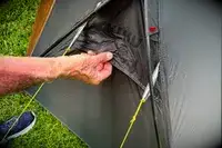 A person pulls a section of the Kuiu Mountain Star 2 Person Tent with the brand logo on it