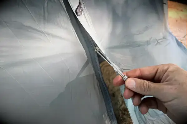 A person zips the Sea to Summit Telos Freestanding Ultralight Tent closed