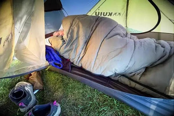 A person sleeps in a sleeping bag inside the Kuiu Mountain Star 2 Person Tent