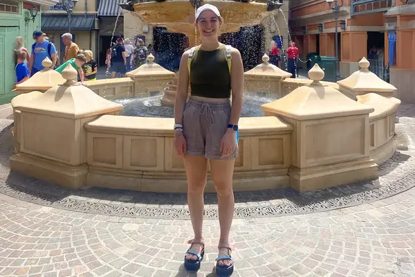 Person standing in front of a fountain in a public plaza