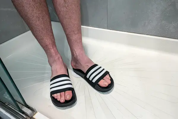 A person stands in the shower while wearing the Adidas Men
