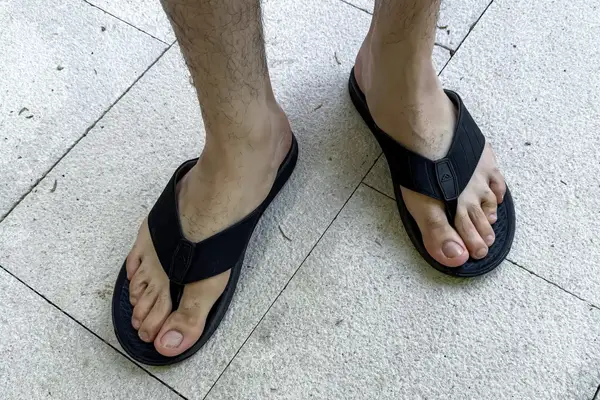 A person wears the Reef The Deckhand sandals on tile