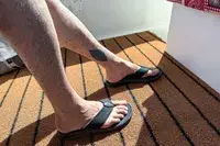 A person wears the Reef The Deckhand sandals on an outdoor rug