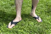 A person wears the Reef The Deckhand sandals in grass