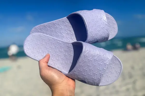 A person holds up a pair of Anmerl Travel Slippers
