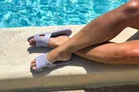 A person wears the Anmerl Travel Slippers while lounging by a pool