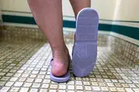 A person wears the Anmerl Travel Slippers in a shower