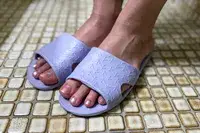 A person wears the Anmerl Travel Slippers on tile
