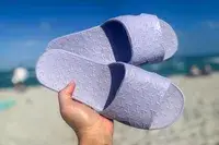 A person holds up a pair of Anmerl Travel Slippers