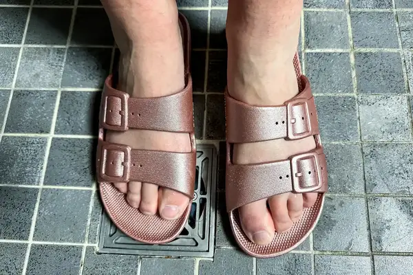 A person wears a pair of Freedom Moses Freedom Slides in the shower