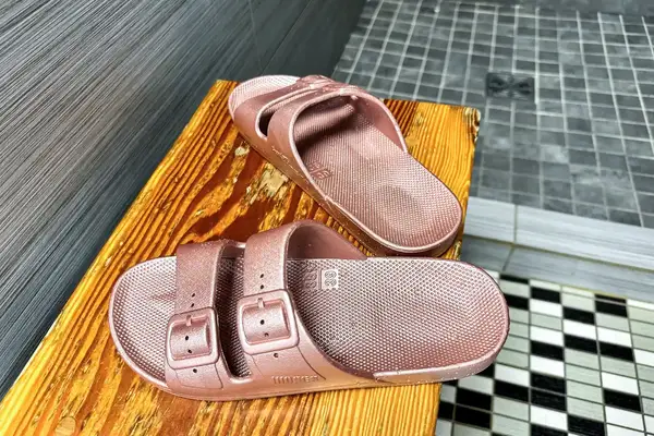 A pair of Freedom Moses Freedom Slides on a wooden bench