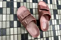 An overhead view of a pair of Freedom Moses Freedom Slides on a tile floor