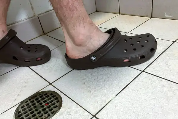 A person showers while wearing the Crocs Classic Clogs