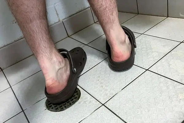 A person wears the Crocs Classic Clogs while showering