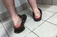 A person wears the Crocs Classic Clogs while showering